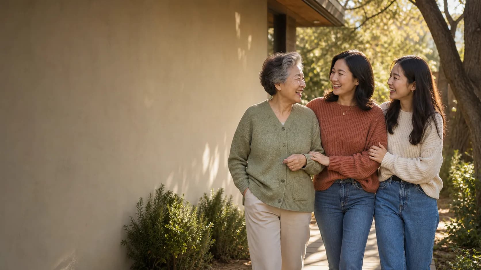 Three generations of women walking together outside in warm afternoon light.