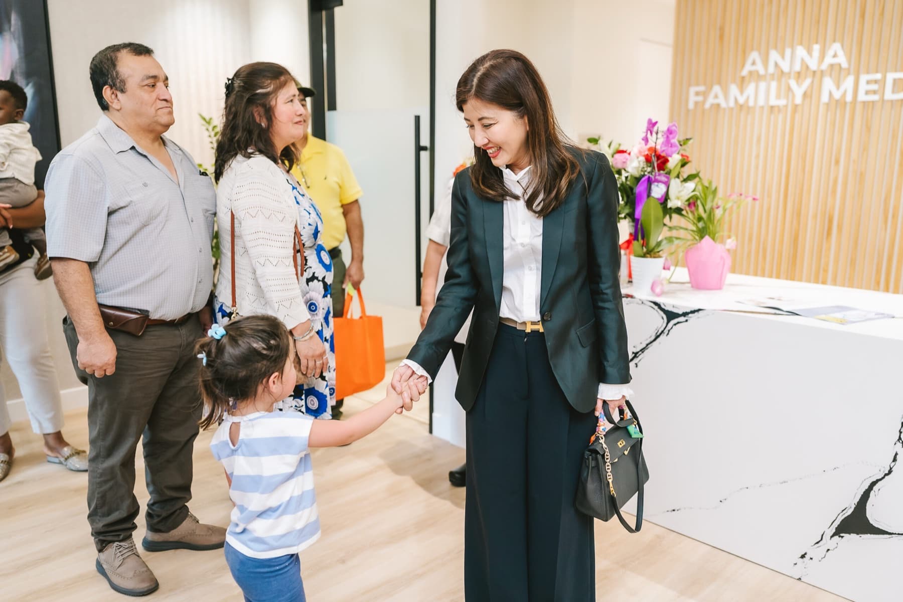 Dr. Anna Le greeting a child and family inside Anna Family Medicine.