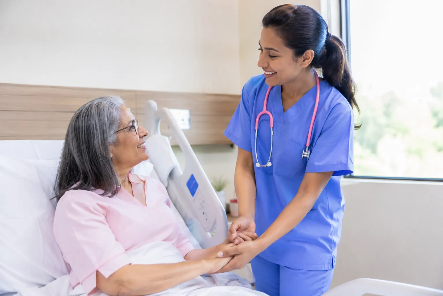 Anna Health nurse holding a patient's hands at the bedside during a warm, attentive visit.