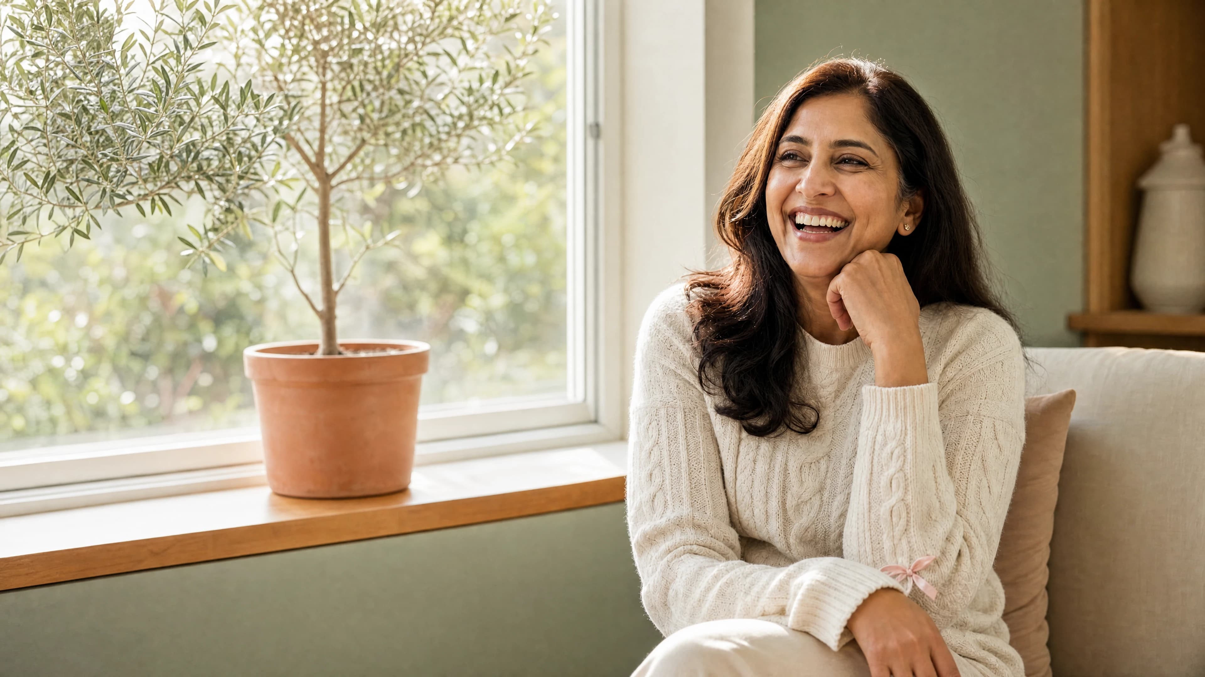 A woman relaxing beside a sunlit window at home.